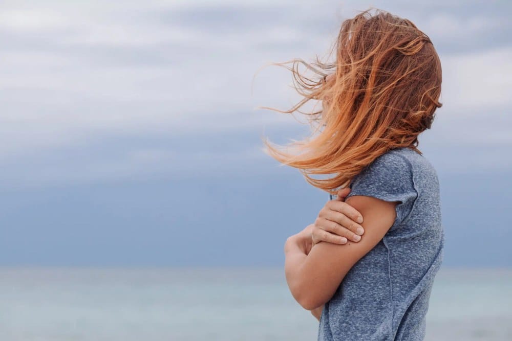 Frau von der Seite im Wind vor blauen Himmel